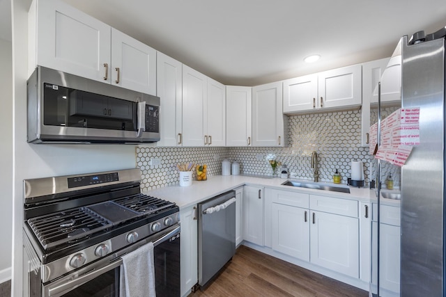 kitchen with stainless steel appliances, white cabinetry, sink, and dark hardwood / wood-style flooring