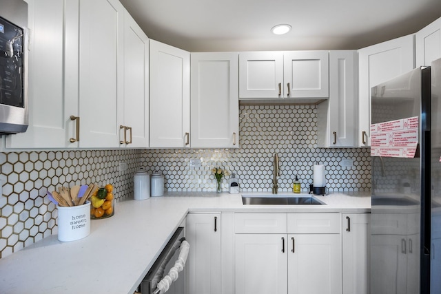 kitchen with backsplash, appliances with stainless steel finishes, sink, and white cabinets