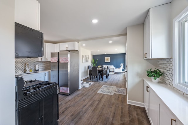 kitchen with stainless steel refrigerator, sink, white cabinets, dark hardwood / wood-style flooring, and gas range