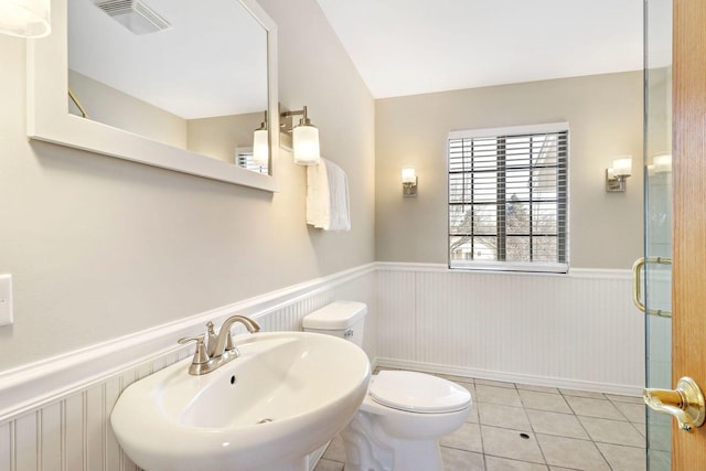 bathroom with tile patterned flooring, visible vents, a wainscoted wall, toilet, and a sink