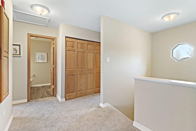 hall featuring attic access, carpet, and baseboards