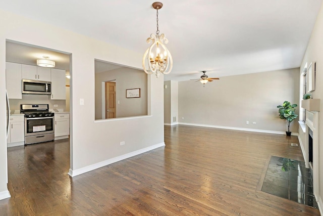 unfurnished living room with baseboards, dark wood-type flooring, and ceiling fan with notable chandelier