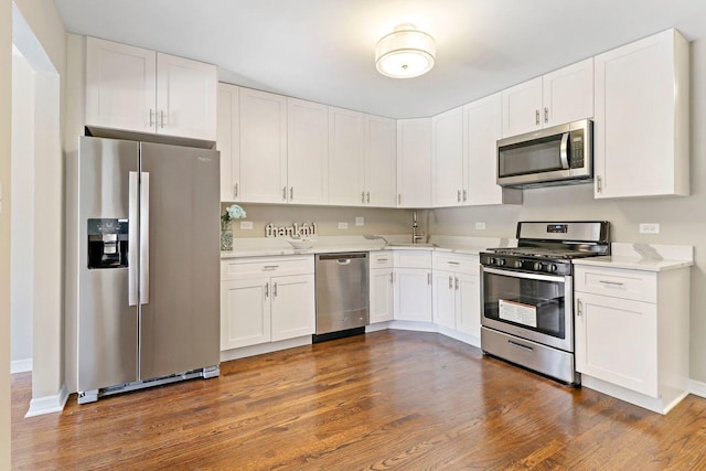 kitchen with baseboards, dark wood-type flooring, appliances with stainless steel finishes, and white cabinetry