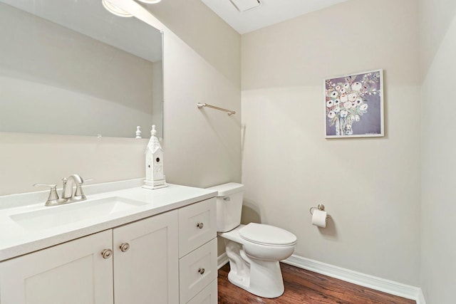 bathroom with baseboards, toilet, wood finished floors, and vanity