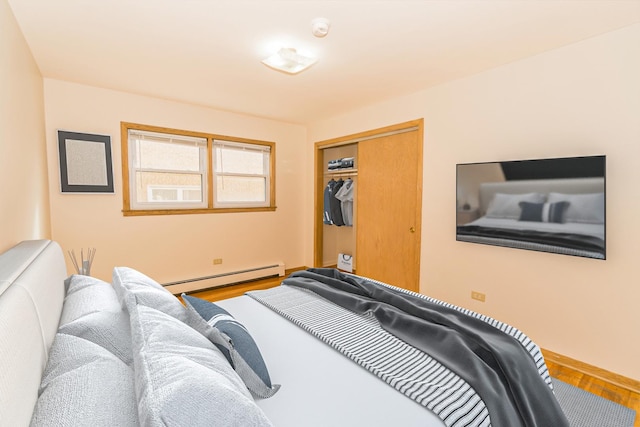 bedroom with hardwood / wood-style flooring, a baseboard heating unit, and a closet