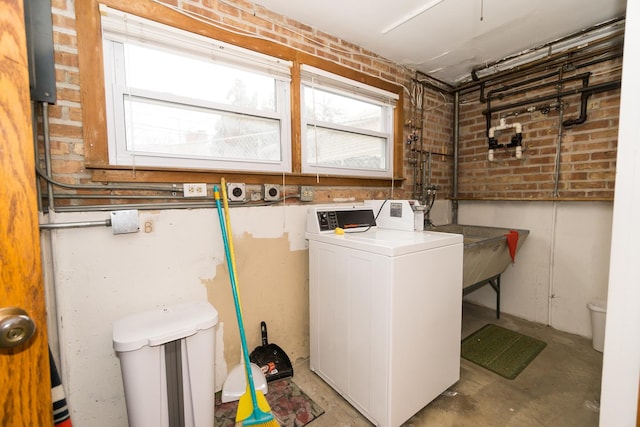 laundry area featuring washer and clothes dryer and brick wall