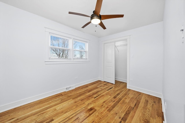 unfurnished bedroom with ceiling fan, light wood-type flooring, and a closet