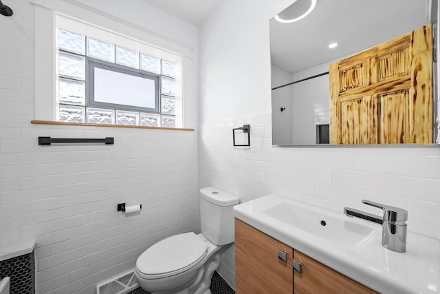 bathroom with vanity, toilet, and tile walls