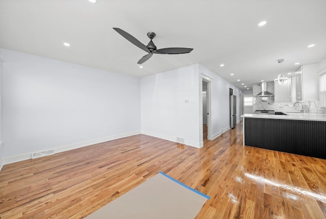 living room featuring ceiling fan, sink, and light wood-type flooring