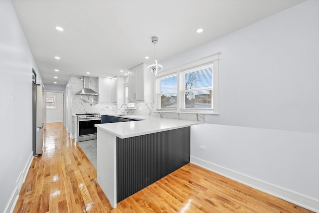 kitchen featuring white cabinetry, stainless steel appliances, a barn door, kitchen peninsula, and wall chimney exhaust hood