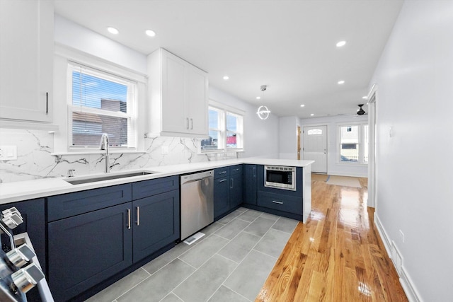 kitchen with pendant lighting, sink, white cabinets, kitchen peninsula, and stainless steel appliances