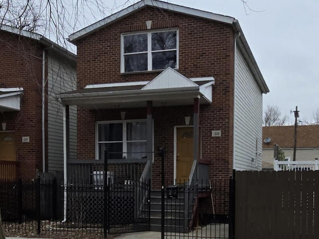 view of front of house featuring covered porch, brick siding, stairway, and a fenced front yard