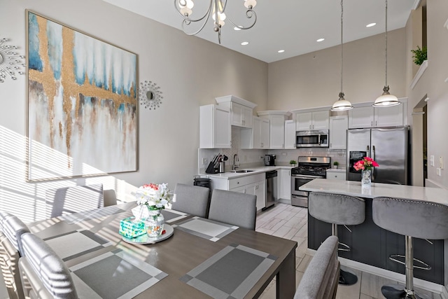 dining space featuring a high ceiling, sink, and a notable chandelier