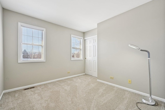 unfurnished bedroom featuring baseboards, visible vents, and light colored carpet