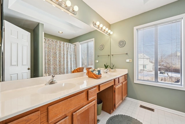 bathroom with double vanity, visible vents, a sink, tile patterned flooring, and baseboards