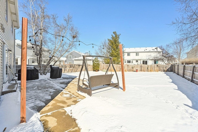 snowy yard featuring a residential view and a fenced backyard