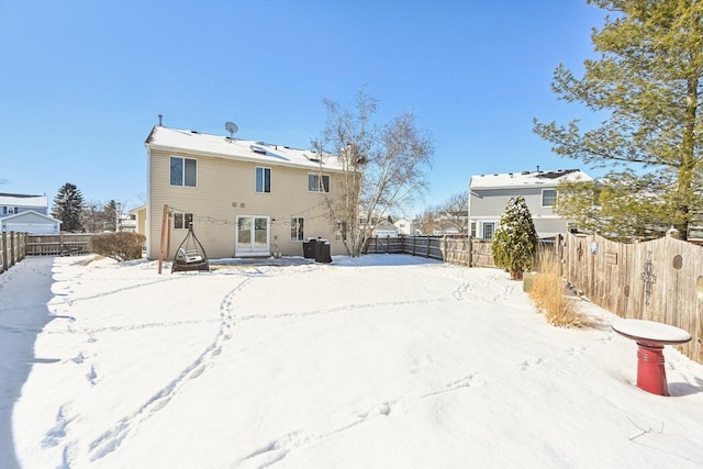 snow covered back of property featuring entry steps and a fenced backyard