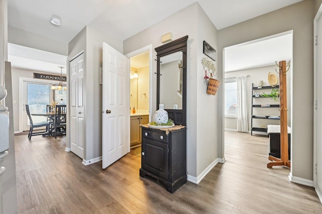 hall with baseboards, a chandelier, and dark wood-type flooring