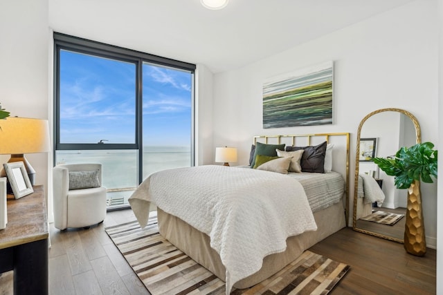 bedroom with a water view, expansive windows, and wood finished floors