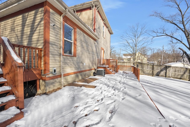 view of snowy exterior featuring a wooden deck and central AC unit