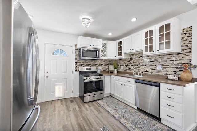 kitchen featuring light hardwood / wood-style flooring, sink, backsplash, stainless steel appliances, and white cabinets