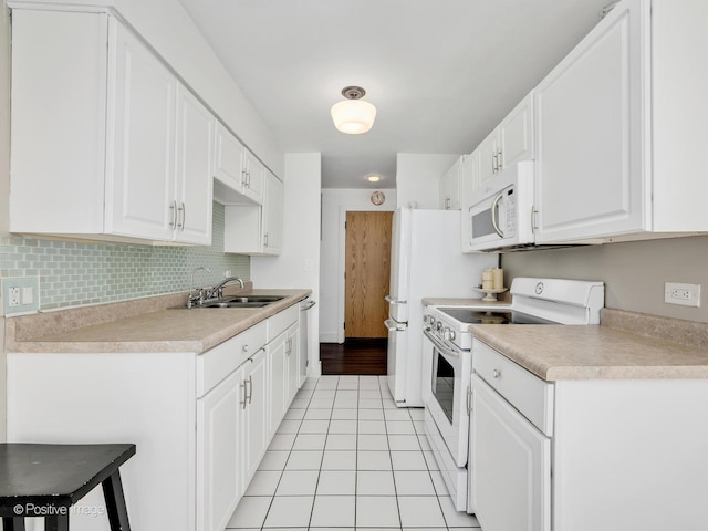 kitchen with white appliances, white cabinets, a sink, and light tile patterned floors