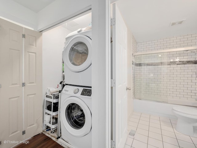 washroom with visible vents, laundry area, stacked washer and clothes dryer, and tile patterned floors