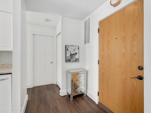 hallway featuring dark wood-style floors, visible vents, and baseboards