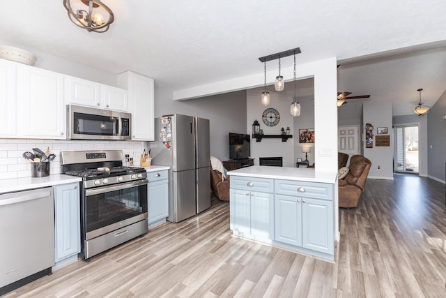 kitchen featuring decorative light fixtures, tasteful backsplash, white cabinetry, lofted ceiling, and stainless steel appliances