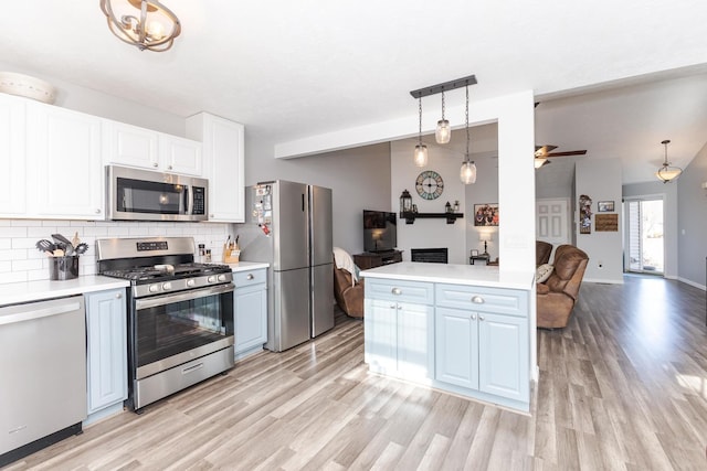 kitchen featuring pendant lighting, white cabinetry, lofted ceiling, decorative backsplash, and stainless steel appliances