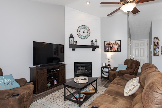 living room with ceiling fan, lofted ceiling, a large fireplace, and light hardwood / wood-style floors