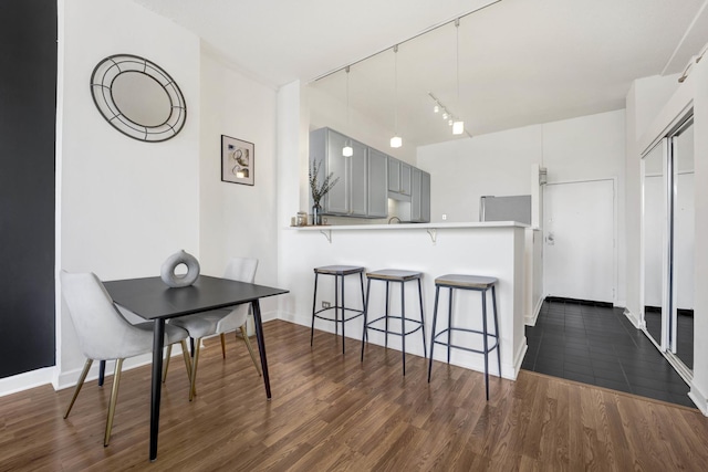 dining area with rail lighting and dark hardwood / wood-style flooring