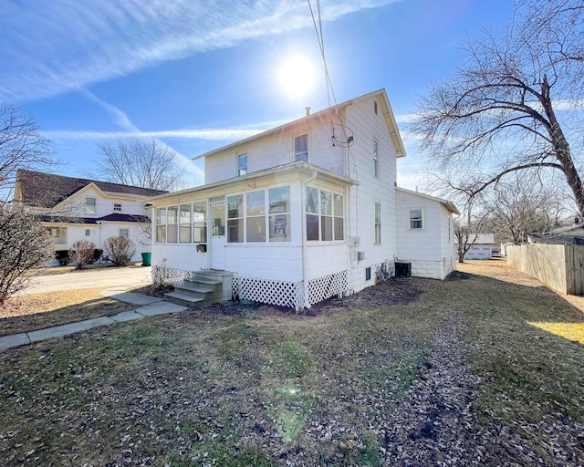 view of front of house with central AC unit, a front lawn, and a sunroom