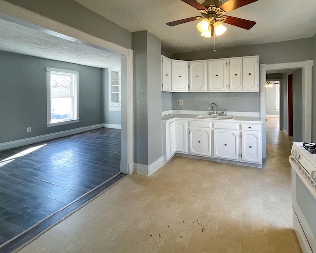 kitchen with white cabinetry, sink, ceiling fan, gas range gas stove, and a textured ceiling