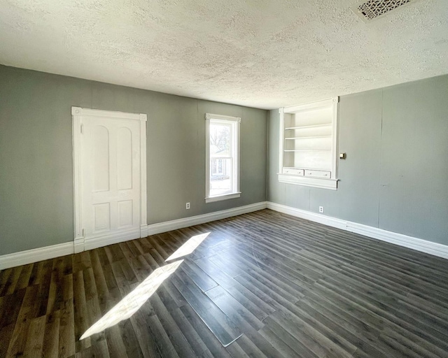 empty room featuring dark hardwood / wood-style flooring, built in features, and a textured ceiling