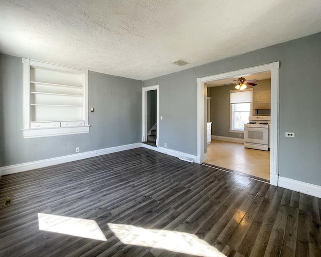 unfurnished room with dark wood-type flooring, built in features, ceiling fan, and a textured ceiling