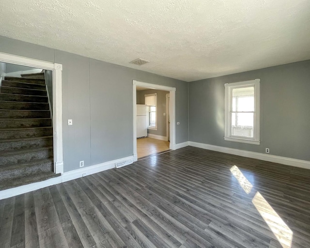 spare room with dark hardwood / wood-style floors and a textured ceiling