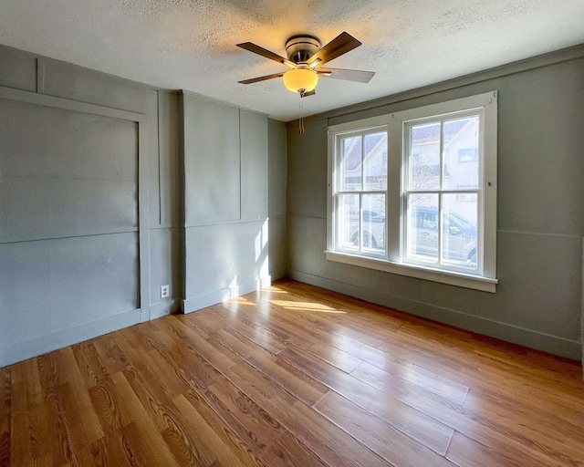 spare room with ceiling fan, light hardwood / wood-style flooring, and a textured ceiling