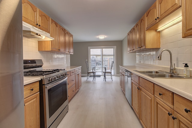 kitchen with backsplash, stainless steel appliances, sink, and light wood-type flooring