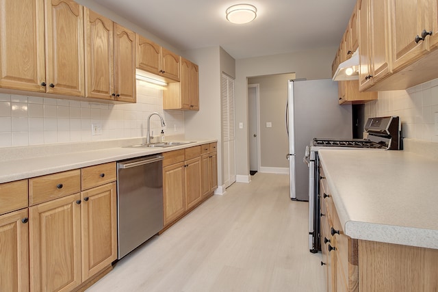 kitchen featuring appliances with stainless steel finishes, light brown cabinetry, sink, decorative backsplash, and light hardwood / wood-style flooring