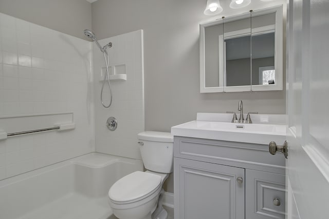 bathroom featuring vanity, a tile shower, and toilet