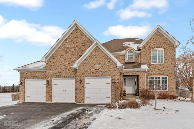 traditional home with brick siding, driveway, an attached garage, and roof with shingles