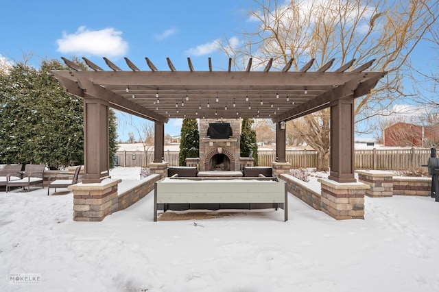 snow covered patio with fence, an outdoor stone fireplace, and a pergola