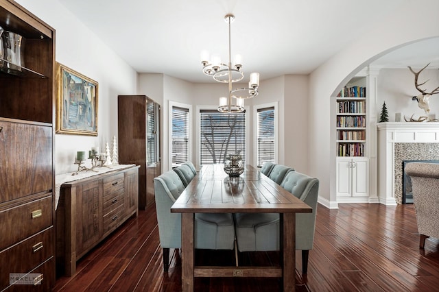 dining space with dark wood-style floors, a fireplace, a chandelier, and built in features