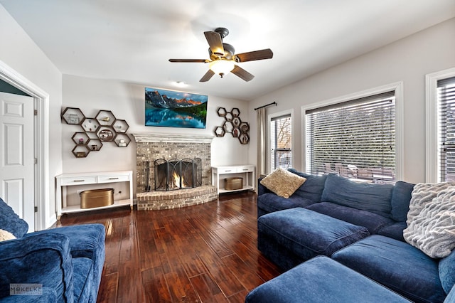 living area featuring dark wood-type flooring, a fireplace, and ceiling fan