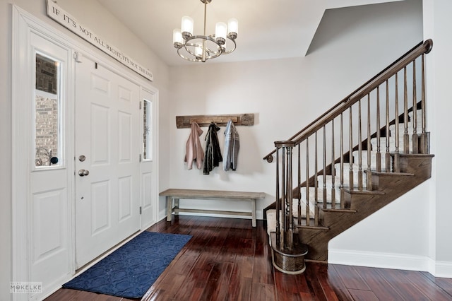 foyer featuring an inviting chandelier, stairs, baseboards, and wood finished floors