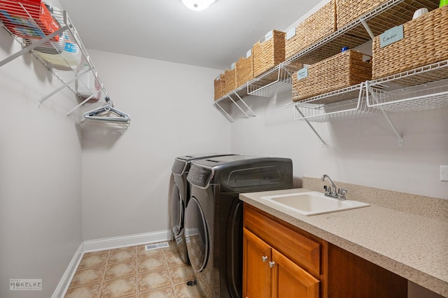 laundry area with visible vents, baseboards, washer and clothes dryer, and a sink