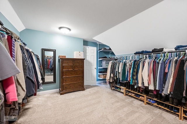 spacious closet with lofted ceiling and light carpet