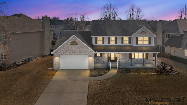 traditional-style home featuring a garage, covered porch, and concrete driveway