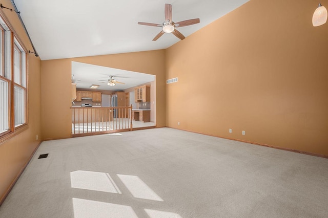 carpeted spare room featuring high vaulted ceiling, visible vents, baseboards, and ceiling fan